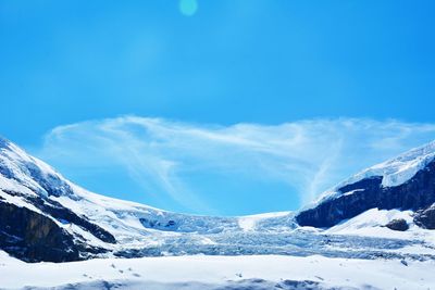 Scenic view of snow covered mountains against blue sky