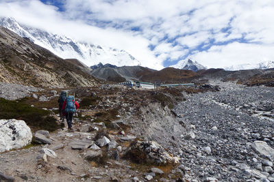 Rear view of people on snowcapped mountains against sky