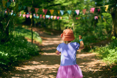 Rear view of girl walking on footpath in forest