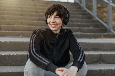 Portrait of teenage girl sitting on staircase against wall