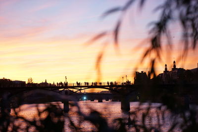 Silhouette bridge over river against sky during sunset