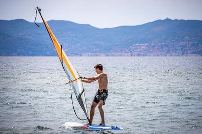 Full length of man standing in sea against mountain
