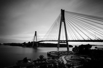 Suspension bridge over river against sky