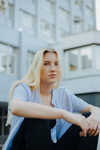 Low angle view of young woman sitting against building