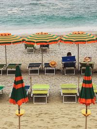 Deck chairs on beach umbrella by sea