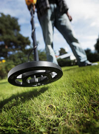 Close-up low section of person with metal detector on grass