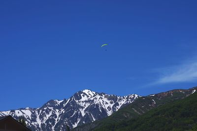 Low angle view of snowcapped mountain against blue sky