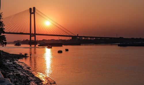 Silhouette bridge over river during sunset