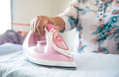 Midsection of woman ironing cloth at home