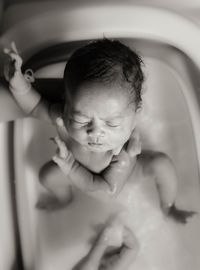 A newborn baby is taking a bath.