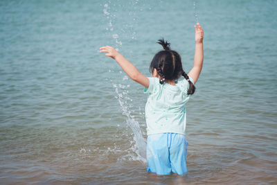 Rear view of woman standing in sea