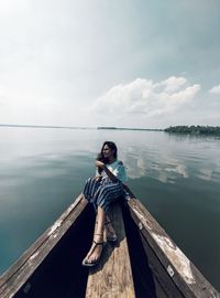 Portrait of man sitting on shore against sky