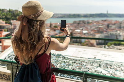 Rear view of woman photographing with smart phone