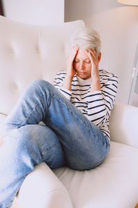 Young woman sitting on sofa at home