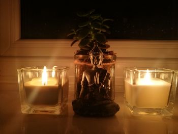 Lit tea light candles on table at home