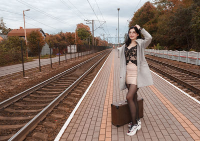 Full length portrait of young woman on railroad tracks