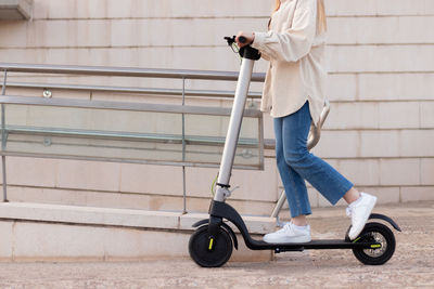 Half cropped view of young unrecognizable woman riding an electric scooter around the city center 