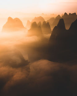Silhouettes of big tall mountains against bright cloudy sky on foggy morning in guilin