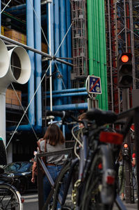 Rear view of woman with bicycle on building in city