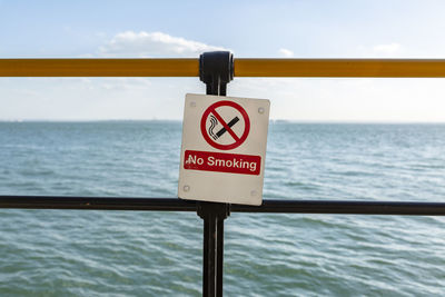 Information sign by railing against sea