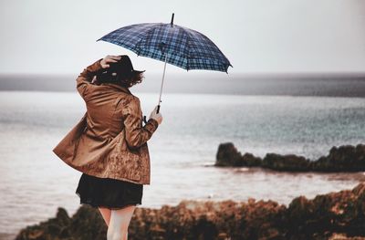 Woman with umbrella overlooking calm sea