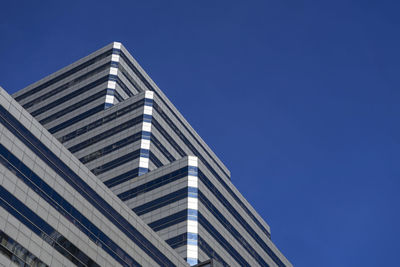 Low angle view of modern building against clear blue sky