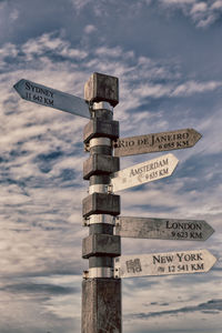 Low angle view of sign on wooden post against sky