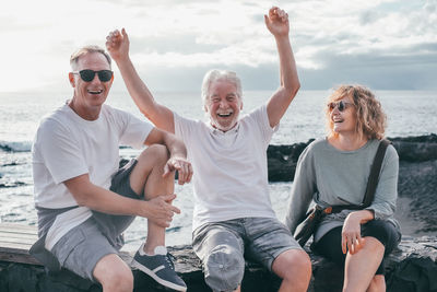 Portrait of smiling friends sitting at beach