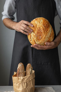 An adult european male baker holds a yeast-free sourdough bread.  bakery or pastry shop