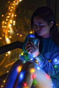 Close-up of girl holding smart phone at night