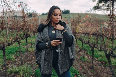 Young woman using phone while standing on field