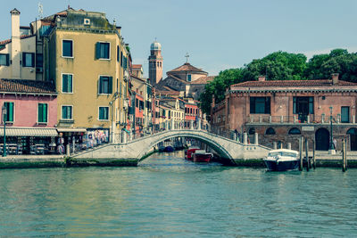 Bridge over river by buildings in city against sky