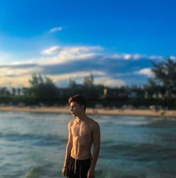 Shirtless man standing against blue sky