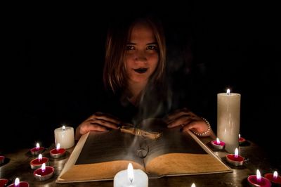 Close-up portrait of young woman holding candles