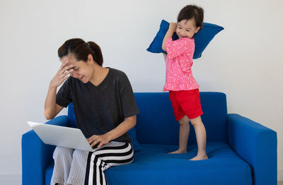 Young woman sitting on sofa against wall