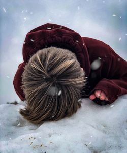 Boy bending on snow covered land