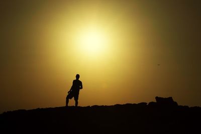 Silhouette man standing against orange sky