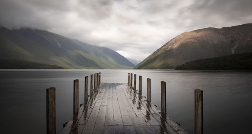 Wooden posts in lake against sky