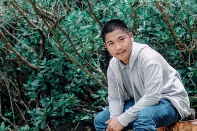 Portrait of young man sitting in forest