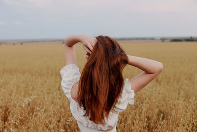 Rear view of woman standing on field against sky