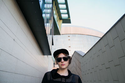 Portrait of young man wearing sunglasses while standing against building