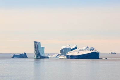 Scenic view of glacier in sea against sky during sunset