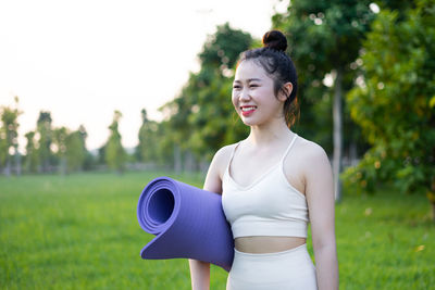 Young woman looking away while standing against trees