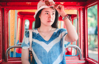 Portrait of beautiful woman standing against red wall