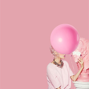 WOMAN STANDING ON PINK BALLOONS AGAINST COLORED BACKGROUND