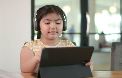 Portrait of young woman using digital tablet while sitting at home