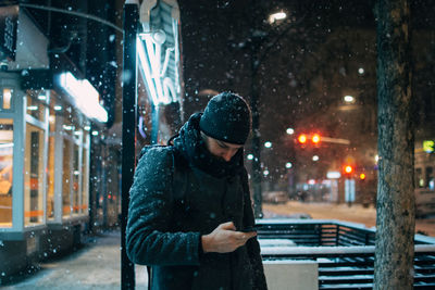 Man using smart phone on city street during winter