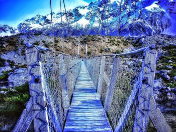 Footbridge in forest against sky