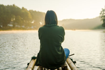 Solo asian woman travel by thai local bamboo boat in tropical forest and lake in autumn season