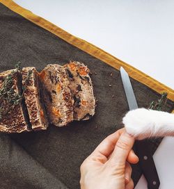 Cropped hand with knife by bread on table